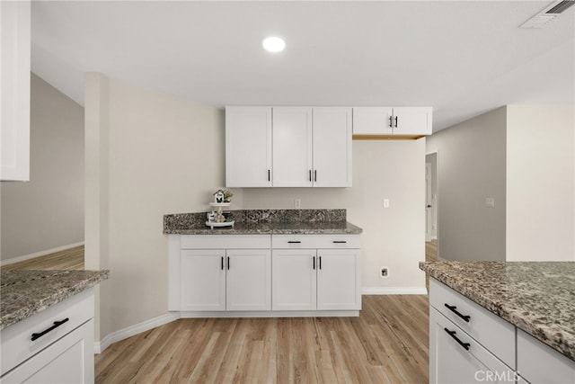 kitchen with light hardwood / wood-style floors, white cabinets, and light stone counters