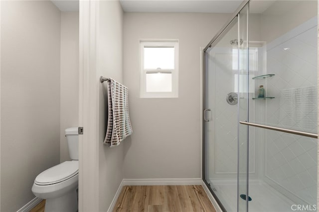 bathroom with toilet, wood-type flooring, and a shower with door