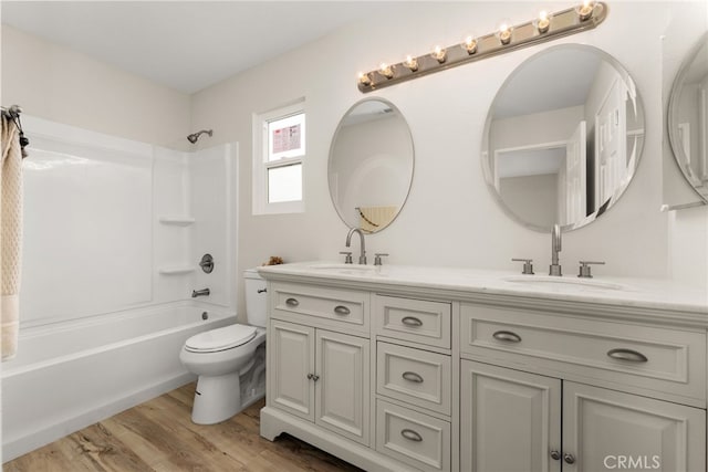 full bathroom with shower / bathing tub combination, vanity, wood-type flooring, and toilet