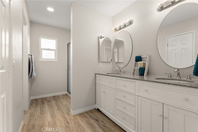 bathroom featuring a shower with shower door, vanity, and wood-type flooring