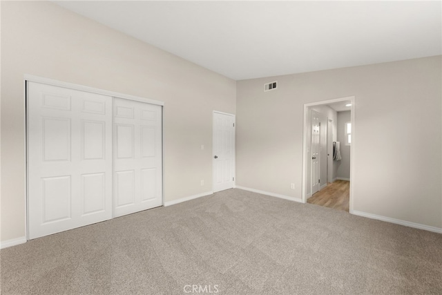 unfurnished bedroom with light carpet, a closet, and vaulted ceiling