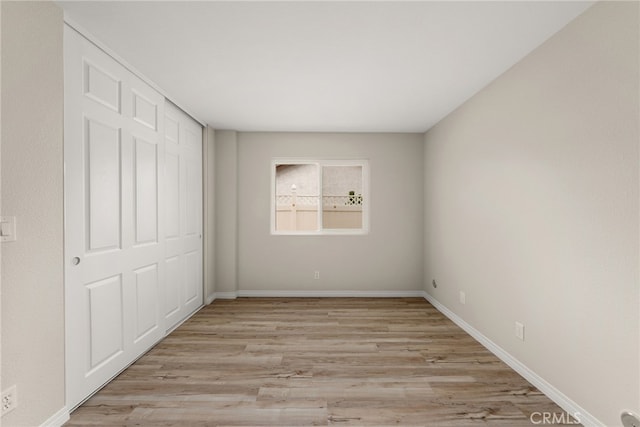 unfurnished bedroom with a closet and light wood-type flooring