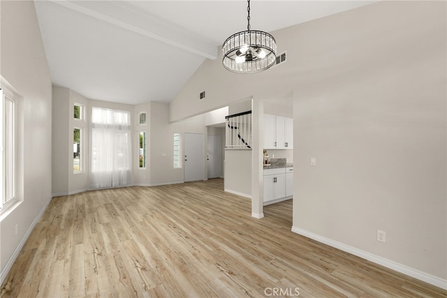 unfurnished living room featuring a chandelier, light hardwood / wood-style floors, beam ceiling, and high vaulted ceiling