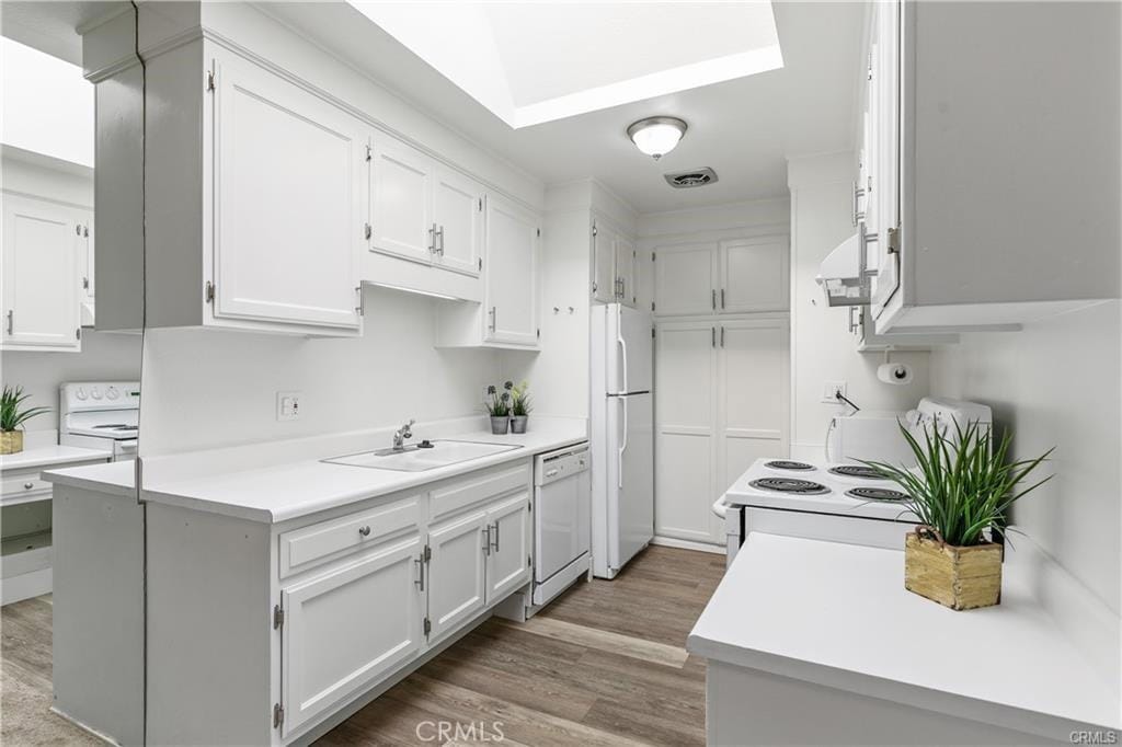 kitchen with ventilation hood, white cabinetry, sink, and white appliances