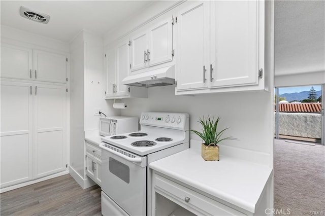 kitchen featuring dark carpet, white cabinets, and white appliances