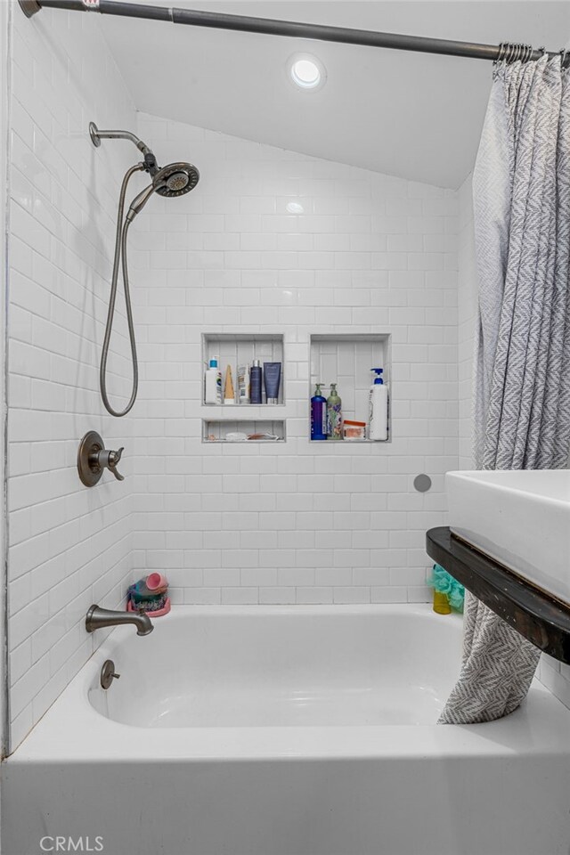 bathroom with lofted ceiling and shower / bathtub combination with curtain