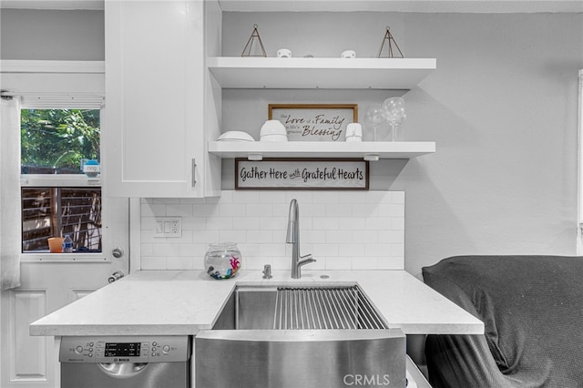 kitchen featuring dishwashing machine, backsplash, sink, and white cabinetry