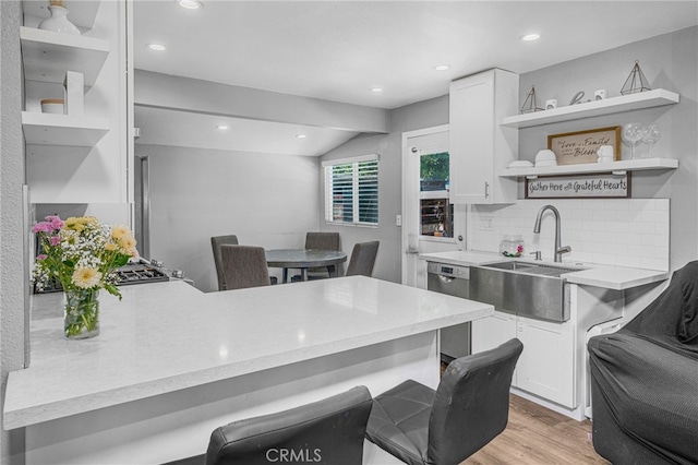 kitchen featuring white cabinets, a kitchen bar, tasteful backsplash, sink, and stainless steel dishwasher