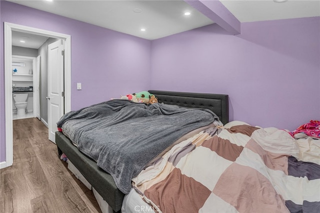 bedroom with beam ceiling and hardwood / wood-style floors