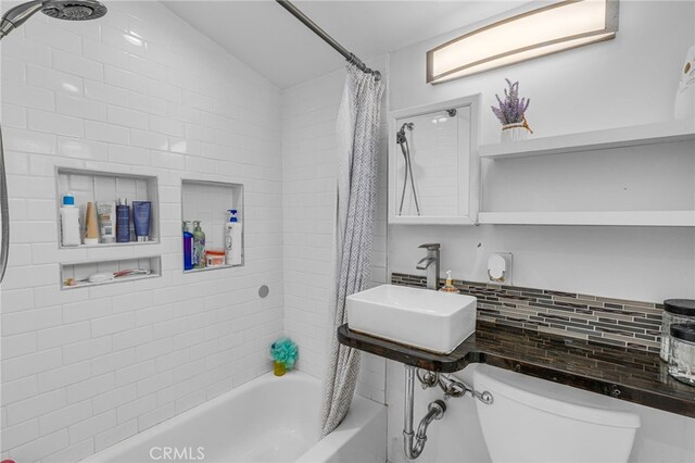 full bathroom featuring shower / bath combo with shower curtain, sink, backsplash, and toilet