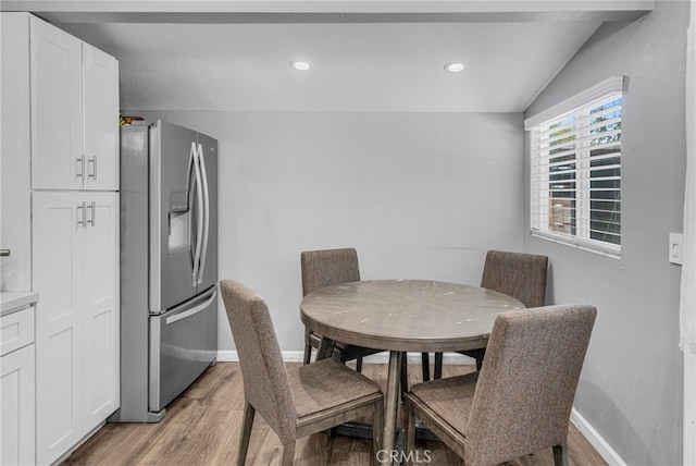 dining space featuring lofted ceiling and light wood-type flooring