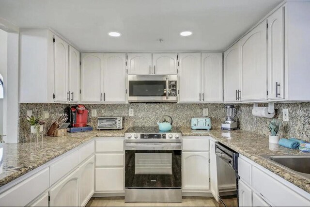 kitchen with stainless steel appliances, backsplash, and white cabinetry