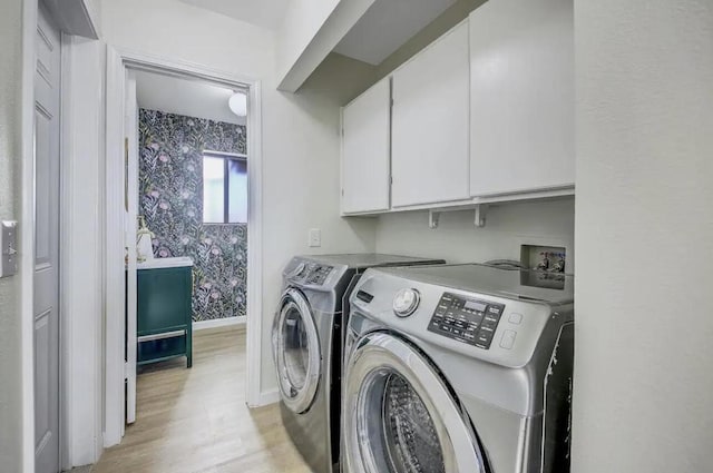 laundry room with washing machine and dryer, cabinets, and light hardwood / wood-style floors