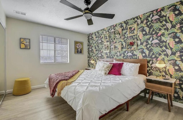 bedroom featuring a textured ceiling, ceiling fan, and wood-type flooring