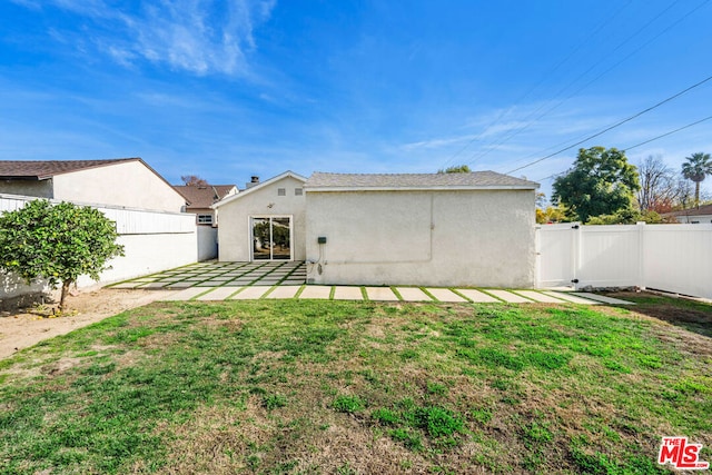 back of house featuring a lawn and a patio area