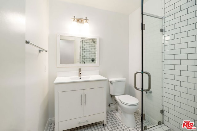 bathroom featuring toilet, vanity, tile patterned floors, and a shower with door