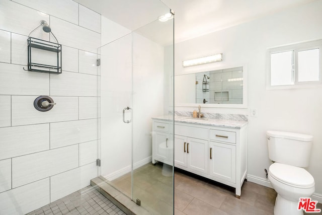 bathroom featuring a shower with shower door, toilet, vanity, and tile patterned flooring