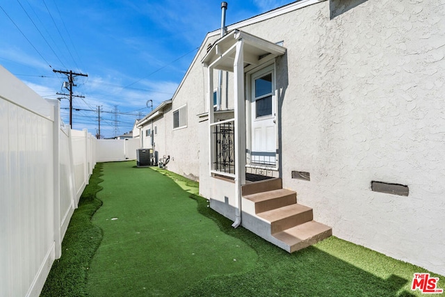 view of side of home featuring cooling unit and a lawn