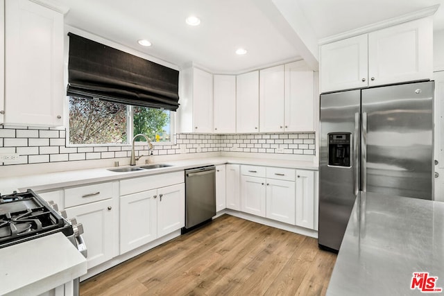 kitchen featuring light wood-type flooring, appliances with stainless steel finishes, white cabinets, and sink