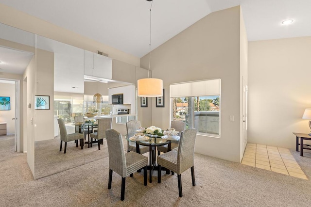 dining room with high vaulted ceiling and light colored carpet