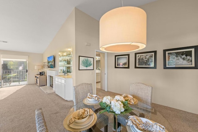 dining space with high vaulted ceiling and light colored carpet