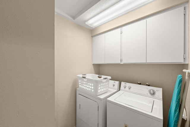 clothes washing area featuring cabinets and separate washer and dryer