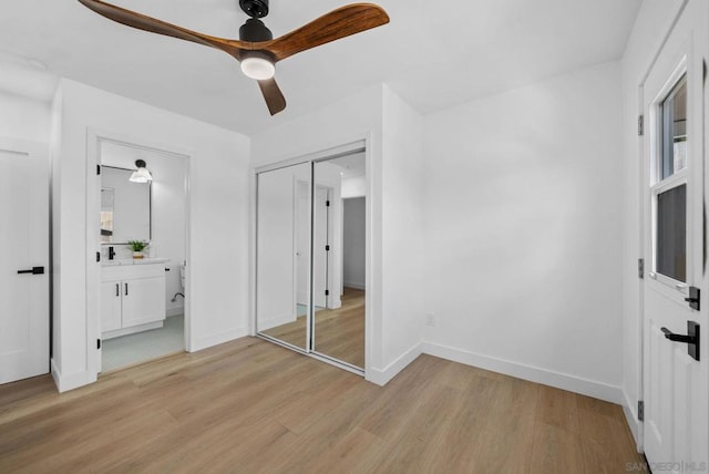 unfurnished bedroom with light wood-type flooring, ceiling fan, a closet, and connected bathroom