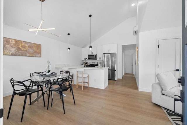 dining space featuring high vaulted ceiling, sink, a chandelier, and light hardwood / wood-style flooring