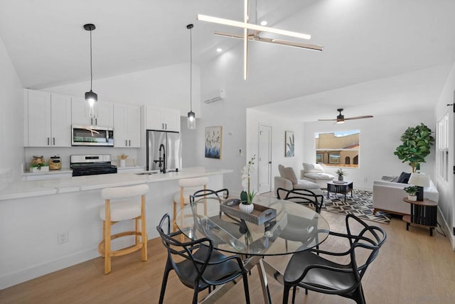 dining area featuring light wood-type flooring, ceiling fan, vaulted ceiling, and sink