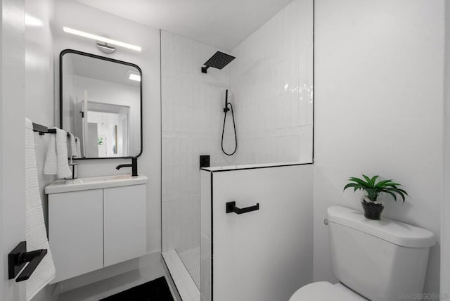 bathroom featuring tiled shower, vanity, and toilet