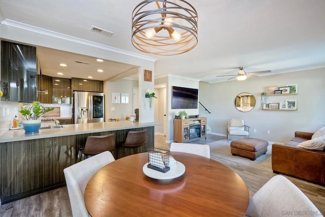 dining area featuring ceiling fan, ornamental molding, and light hardwood / wood-style floors