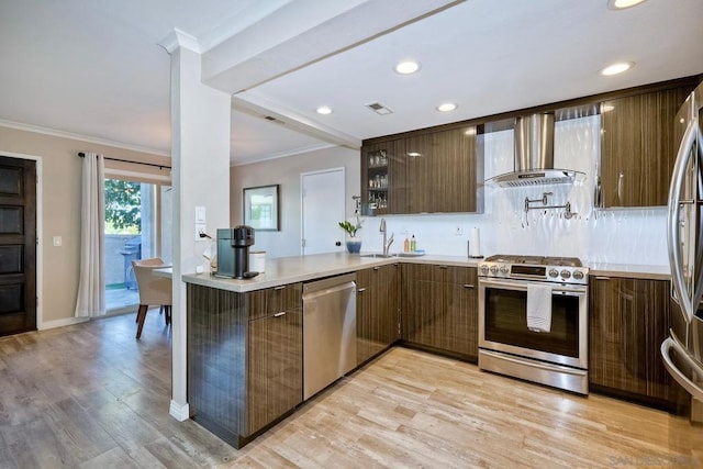 kitchen with kitchen peninsula, stainless steel appliances, wall chimney exhaust hood, crown molding, and sink