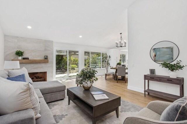 living room with a fireplace, light hardwood / wood-style floors, and an inviting chandelier