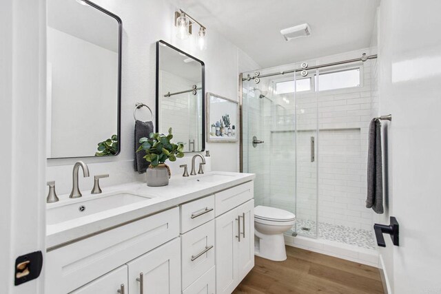 bathroom featuring toilet, a shower with shower door, wood-type flooring, and vanity