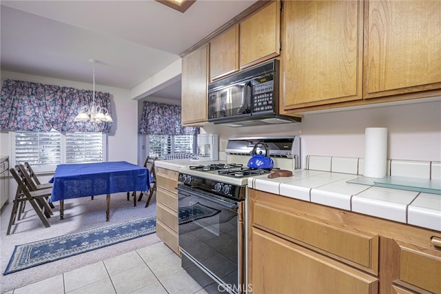 kitchen featuring tile counters, light tile patterned floors, an inviting chandelier, and gas stove