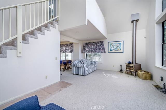 carpeted living room with a high ceiling and a wood stove