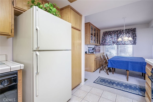 kitchen featuring white fridge, tile counters, light tile patterned flooring, hanging light fixtures, and a chandelier