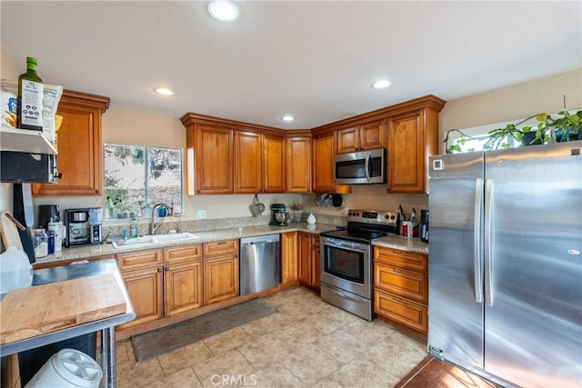 kitchen with appliances with stainless steel finishes, light stone counters, and sink