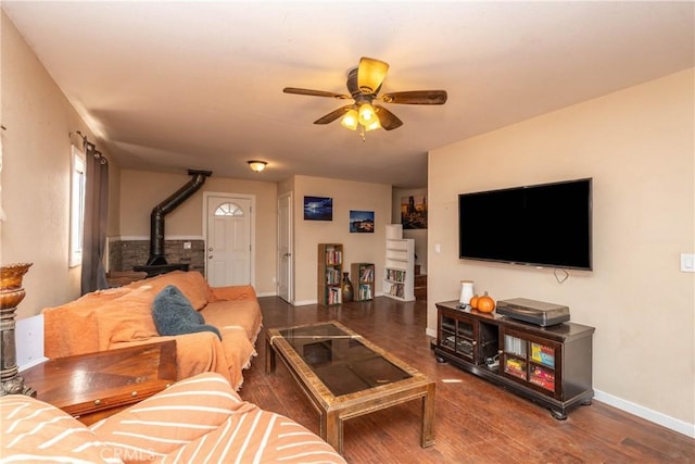 living room with ceiling fan, a wood stove, and hardwood / wood-style floors