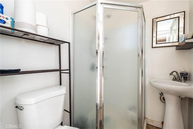 bathroom with toilet, an enclosed shower, and sink