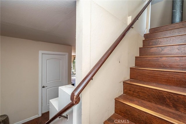 stairway featuring a textured ceiling