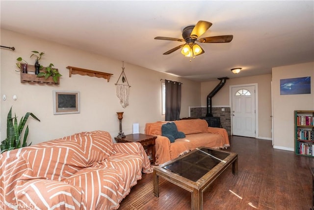 living room with ceiling fan, a wood stove, and dark hardwood / wood-style floors