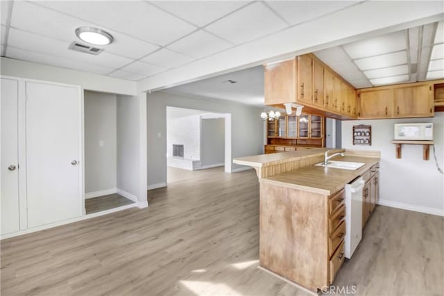 kitchen with kitchen peninsula, white appliances, light wood-type flooring, a drop ceiling, and sink