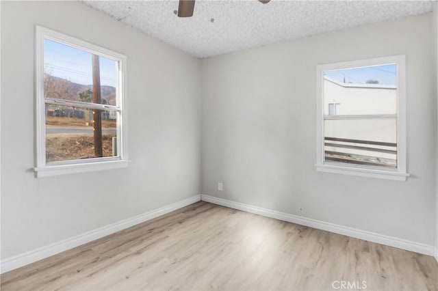 empty room with ceiling fan, plenty of natural light, and light hardwood / wood-style floors