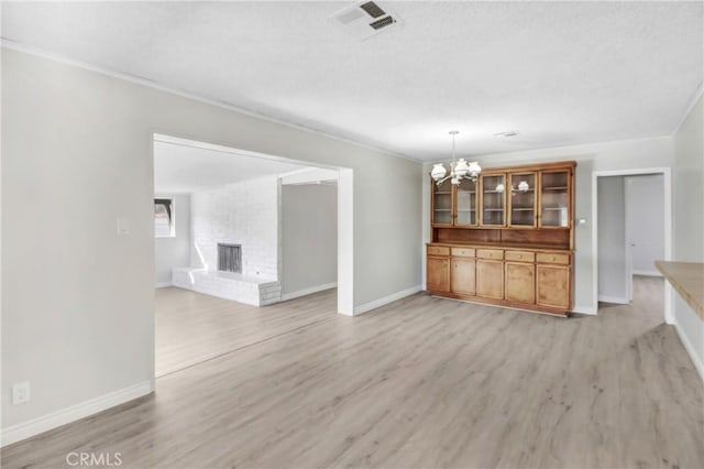 unfurnished living room featuring a brick fireplace, an inviting chandelier, and light wood-type flooring