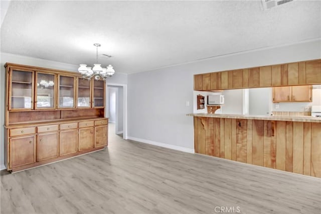 kitchen with decorative light fixtures, kitchen peninsula, a chandelier, light hardwood / wood-style flooring, and a breakfast bar area