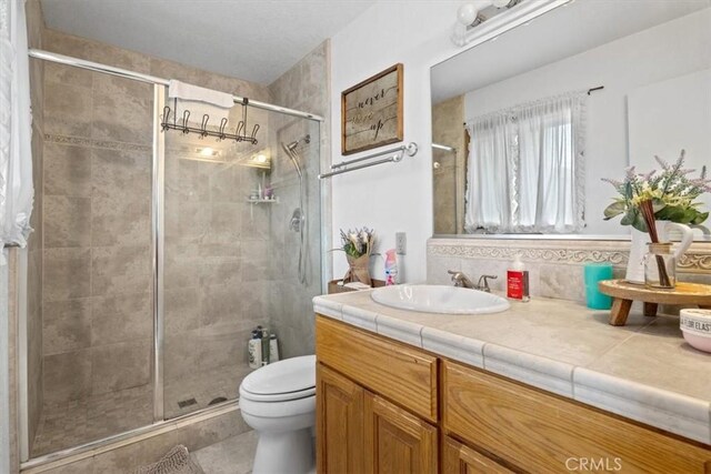 bathroom with toilet, decorative backsplash, a shower with shower door, and vanity