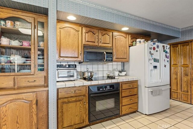 kitchen featuring decorative backsplash, black appliances, tile countertops, and light tile patterned flooring