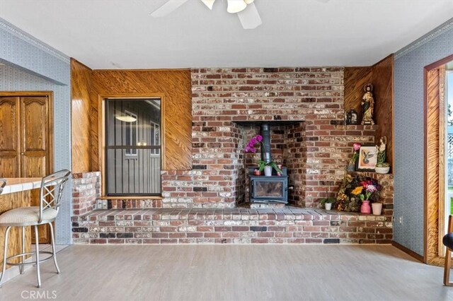 unfurnished living room featuring ceiling fan, ornamental molding, wood-type flooring, and wood walls