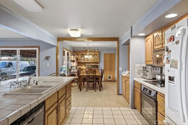 kitchen with pendant lighting, crown molding, white refrigerator with ice dispenser, tile counters, and black oven